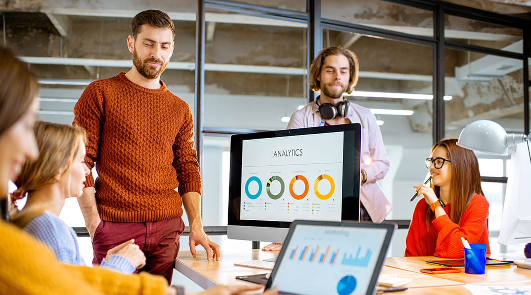 Marketing team reviewing PPC analytics and performance data on a desktop screen during a strategy meeting.